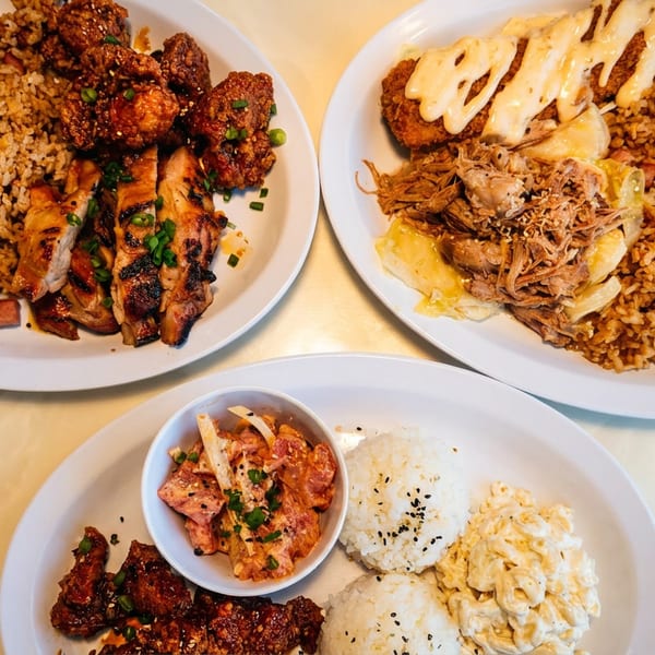 Three plates of Hawaiian food, including fried chicken, grilled chicken, pulled pork, rice, and macaroni salad.